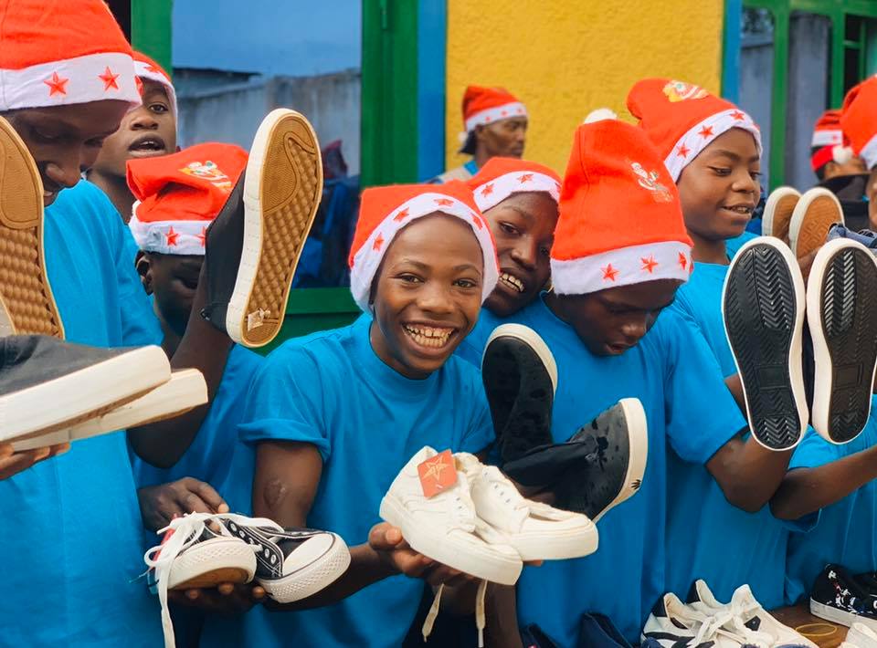 Street kids with Santa hats on, holding some new shoes